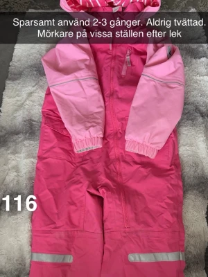 Rosa skaloverall med huva och reflexer - En rosa skaloverall i två nyanser med huva och dragkedja framtill. Overallen har elastiska muddar vid ärmarna och reflexdetaljer på benen och armarna. Perfekt för utomhusaktiviteter och lek. 🌸 Använd 2-3 gånger. Otvättad, lite smuts på.storlek 116.