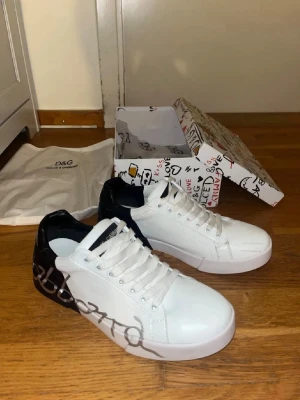 Dolce & Gabbana vita sneakers med svart detalj - Snygga vita sneakers från Dolce & Gabbana med svart hälparti i läder.
