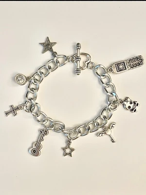 Silvrigt berlockarmband  - Säljer ett chunky armband i silverfärgad metall med flera olika berlocker. Armbandet har ett toggle-lås. Du får det i en liten tyg påse.