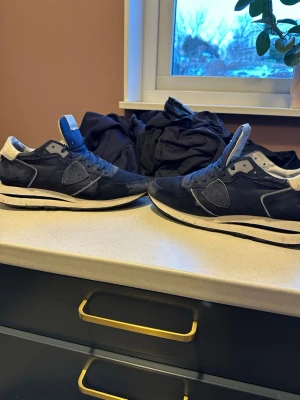 Mörkblå sneakers med vit sula - Snygga mörkblå sneakers med vit sula och detaljer i mocka och textil. Skorna har en klassisk låg profil och vita partier vid häl och plös. Perfekta för dig som gillar stilrena och sportiga skor. NY PRIS 3000 