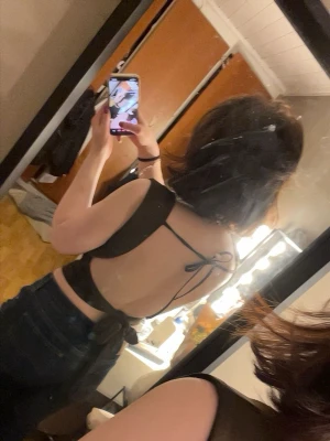 Mörkbrun croppad topp med snörning - Säljer en mörkbrun croppad topp med breda axelband och snygg snörning i ryggen. Toppen har en tight passform och är perfekt för dig som vill ha en enkel men trendig look. Materialet känns mjukt och stretchigt, troligen polyester.