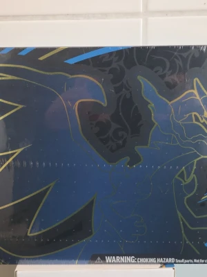 Pokémon Mega Charizard X ex Box - Säljer en Mega Charizard X ex Ultra-Premium Collection från Pokémon TCG. Boxen är blå och svart med guld- och blådetaljer och innehåller bland annat foil promo cards, sleeves, playmat och samlarmynt. Perfekt för dig som gillar Pokémonkort och samlarprylar.