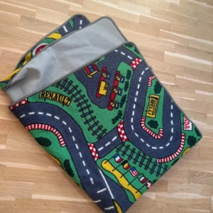 Barnmatta med bilbana 133x160 cm - Färgglad barnmatta med klassiskt bilbanemotiv, perfekt för lek. Mått: 133x160 cm. Mattan är i bra skick med mindre tecken på användning på undersidan. Tillverkad i nylon, halkfri baksida. Passar utmärkt i barnrummet.