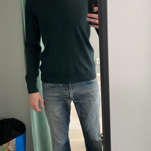 Mörkgrön cashmere tröja J.Lindeberg - Snygg mörkgrön cashmere tröja från J.Lindeberg i storlek s. Klassisk rund hals och ribbade muddar vid ärmslut och nederkant. Väldigt bra skick men litet hål i armhålan men det syns ej