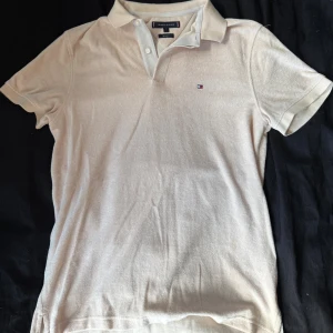 Beige frotte piké från Tommy Hilfiger S - Snygg beige pikétröja från Tommy Hilfiger i regular fit. Tröjan har korta ärmar, klassisk krage och knappar framtill. Materialet är mjukt och känns som frotté, med diskret Hilfiger-logo broderad på bröstet. Perfekt för en clean och chill stil.