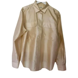 Beige sidenskjorta Totême - Stilren beige skjorta från Totême i siden. Skjortan har klassisk krage, två stora bröstfickor och dolda knappar framtill. Långärmad och med avslappnad passform, perfekt för en clean och modern look.