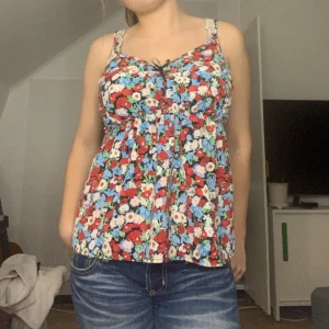 Blommig linnetopp med rosett  - Söt linnetopp med färgglatt blommönster. Jag säljer den pga att jag inte använder den längre. Den är i bra skick och jättefin till sommaren 💕