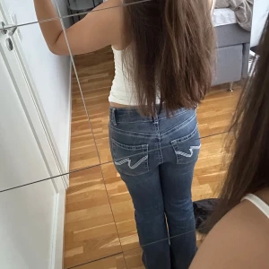 Bootcut lågmidjade jeans med broderade fickor Nelly - Säljer ett par trendiga Nelly jeans som är blå med låg midja. Jeansen har snygga broderade detaljer på bakfickorna. Materialet är jeans och passformen är normal med utsvängda ben. Inga skador på jeansen, säljer då de inte kommer till användning. 