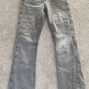 Grå jeans från Gina Tricot, stl 152 - Snygga grå jeans från Gina Tricot i bootcut modell. Jeansen har klassisk femficksdesign, dekorativa sömmar på bakfickorna och en cool knapp med blomdetalj. Tillverkade i bomull med en skön jeanskänsla. Perfekta för dig som gillar en avslappnad stil.