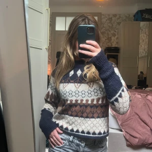 Mönstrad stickad tröja i lusekofta -stil - Säljer en stickad tröja i lusekofta/norgetröja stil, med snyggt mönster i marinblått, brunt och beige. Tröjan har rund hals, långa ärmar och en klassisk nordisk design. 