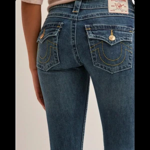 True religon jeans - Snygga blå jeans med bootcut-modell och markerade guldiga sömmar på bakfickorna. Jeansen har låg midja, använda tre gånger bara!!!