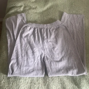 Grå mjukisbyxor med resårmidja - Grå mjukisbyxor med elastisk resår i midjan och raka ben. Materialet är mjukt och bekvämt, perfekt för chill dagar hemma eller när du vill vara extra comfy. Byxorna har en enkel design utan synliga fickor eller detaljer. Storlek xxs-s