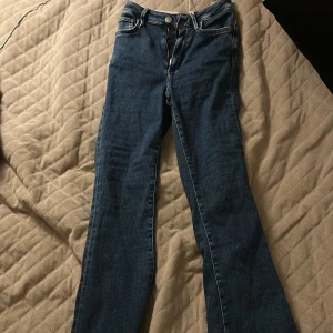 Blåa flare jeans från Amisu XS/S - Säljer ett par blåa JP Peachy Flare jeans från bikbook i storlek XS/S. Jeansen har klassisk femficksdesign, hög midja och utsvängda ben. Snygg denim med dragkedja och knapp framtill, perfekta för en trendig look.