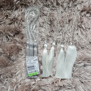 Gardinomtag vit och silvergrå 2pack - Bilderna visar ett paket med dekorativa tofsar i silvergrå färg, tillverkade av 100% polyester med akryl. Produkten är avsedd för dekoration och levereras i originalförpackning. Inga synliga defekter eller slitage. Perfekt för gardiner.