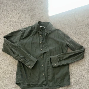 Linneskjorta från Skagen clothing - Olivgrön skjorta från Skagen i storlek XS. Tillverkad i svalt linne med klassisk krage, knäppning framtill och långa ärmar med manschettknappar. Nypris ca 1000kr. Skjortan är i gott skick men vid minsta fundering tveka inte på att kontakta mig!