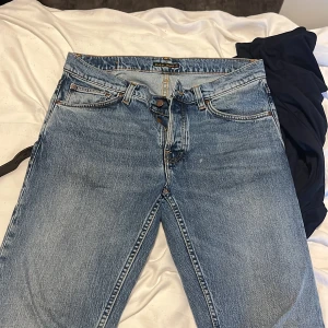 Nudie Jeans Solid Ollie Worn Vintage - Säljer ett par ljusblå Nudie Jeans Solid Ollie i modellen Worn Vintage. Klassisk femficksdesign, snygga kontrastsömmar och broderade bakfickor. Tillverkade i 99% bomull och 1% elastan för lite stretch. Perfekta jeans för dig som gillar en avslappnad look.