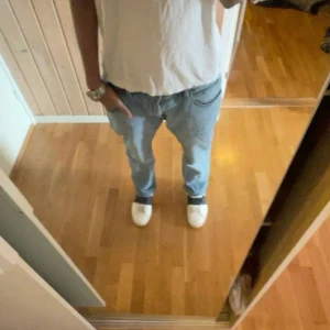 Replay Anbass Jeans - Säljer ett par ljusblå jeans från Replay i klassisk femficksmodell. Jeansen har raka ben och slim/regular passform, med snygga slitningar framtill. Storlek 34/32. Skriv vid frågor, priset är ej hugget i sten!