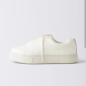 Vita sneakers från Eytys - Snygga vita sneakers från Eytys med chunky platt sula och diskret lila detalj på hälen. Skorna har snörning och är tillverkade i ett strukturerat syntetmaterial som ger en modern och clean look. Perfekta för dig som gillar minimalistisk stil.  Skriv privat för egna bilder! ❤️ vill bli av med så snabbt som möjligt, pris kan diskuteras 