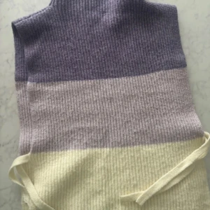 Väst/halsduk - Supermjuk stickad väst/halsduk med polokrage som har knytband i midjan och kontrasterande färger. Längd i M 53cm passar från storlek XS-L Djur och rökfri hem 