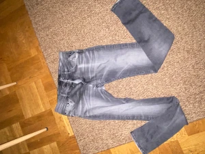 Replay grå jeans, storlek 28 30 - Snygga Replay  jeans i grå tvätt med coola slitningar och klassisk femficksdesign. Bakfickan har Replay-loggan broderad. Jeansen har slim fit passform och är tillverkade i mjukt jeanstyg med stretch för extra komfort.