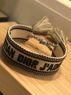 Christian dior - Riktigt fräscht Armand från Christian dior. Armbandet är i vit färg med svarta detaljer. Det är också justerbart så att det passar vem som helst! Skickar samma dag eller dagen efter köp.