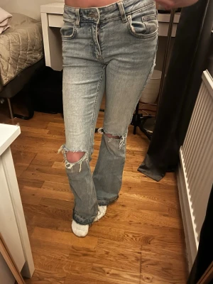 Jeans med hål  - Snygga low-waist boot jeans i storlek XS med hål på knäna. Längst ner är de uppsprättade pga att jag tycker det är snyggt med jeans som ser ut så där nere och för att dom ska bli lite längre då dom är korta i storleken.