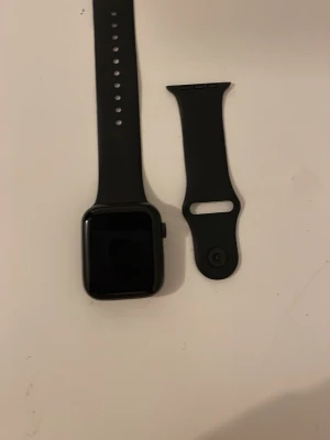 Smart Watch (okänt märke) - Svart smartklocka med silikonarmband och USB-laddare. Skärmen är i gott skick och visar meddelande om låg batterinivå. Inga synliga repor eller skador. Perfekt för dig som vill ha en enkel och stilren smartklocka till vardags.