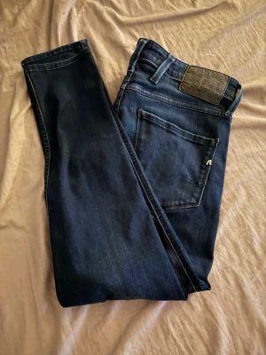 Mörkblå Replay jeans straight fit 30/30 - Snygga mörkblå jeans från Replay med klassisk femficksdesign och raka ben. Jeansen har en diskret logga på bakfickan och är tillverkade i mjukt denimtyg som sitter skönt. Perfekta för dig som gillar en stilren och tidlös look.