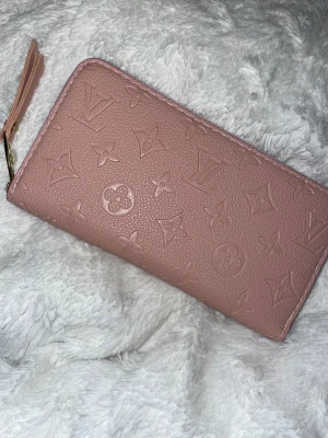 Rosa  plånbok med många fack - Superfin rosa plånbok  i präglat skinn med klassiskt mönster. Plånboken har dragkedja i guld, flera fack för kort och mynt. Inspirerad, därav priset. OBS! se ALLA bilder för skick! Skickar med dustbag OM jag hittar den. ❣️