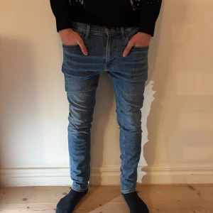 Blå jeans från Lee - Snygga blå jeans från Lee med klassisk femficksdesign och brunt Lee-läderpatch bak. Slim fit