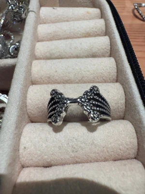 Silvrig ring med vingeformad design - Cool ring i silverfärgad metall med detaljerad vingeformad front. Ringen har små upphöjda prickar som ger en unik struktur och edgy känsla. Perfekt accessoar för dig som vill sticka ut med något annorlunda och stilrent.