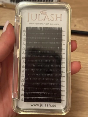 Julash ögonfransförlängning 13mm - Golden Edition Eyelash Extensions från Julash, svarta fransar med D-böj, tjocklek 0.05 mm och längd 13 mm. Perfekt för volymfransar och ett fylligt resultat. Kommer i en transparent och guldig ask med flera rader fransar.