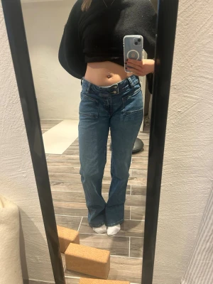 Blå bootcut jeans med fickor - Snygga blå jeans med bootcut passform och stora framfickor. Byxorna har hög midja och klassisk femficksdesign baktill. Jeansen är tillverkade i jeansmaterial och har en rak, något utsvängd siluett nedtill. Perfekta för dig som gillar retrovibbar och bekväm stil.🩷