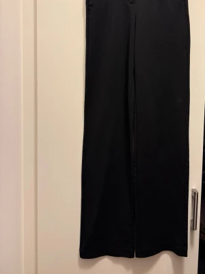 Svarta raka byxor från Vero Moda XS - Svarta byxor från Vero Moda i storlek XS med rak passform och midwaist. Snyggt stilrena och enkla att matcha med olika outfits. Materialet är mjukt och har en lätt stretch för extra komfort. Perfekta för dig som gillar minimalistisk och clean look.