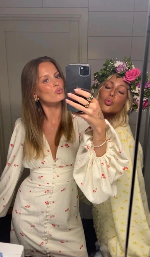 Vit kortklänning med blommigt mönster - Superfin vit kortklänning med små röda blommor, djup v-ringning och puffiga långärmar. Klänningen har knappar längs hela framsidan och markerad midja som ger en snygg siluett. Materialet är lätt och har en lite strukturerad känsla.