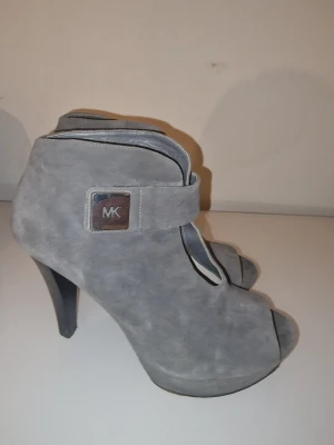 Gråa klackar i mocka från Michael Kors - Snygga grå pumps från Michael Kors i mjuk mocka med öppen tå och hög klack. Inköpta I New York. 