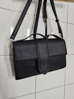 Liten väska - Svart axelremsväska med detaljer och magnetstängning. Köpt på Ur&Penn eller Glitter.