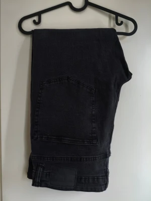 Svarta jeans Slimmy W36 - Svarta jeans från Lager 157 i modell Slimmy med klassisk femficksdesign och diskret svart patch bak. Jeansen har en slim passform och är tillverkade i mjukt jeanstyg som sitter skönt hela dagen. Perfekt för dig som gillar stilrena och tidlösa plagg. W36L34 är storleken på etiketten men är uppsydda i butik av Lager 157 till L30 ca 100 cm hela byxan bild finns på längd av byxorna, byxorna är som nya.