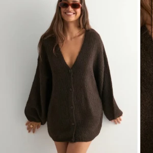 Brun stickad kofta från Nelly - Helt ny med prislapp. Mysig brun kofta från Nelly med volym i ärmarna och djup v-ringning. Koftan är stickad, har knappar framtill och en loose passform som ger en chill vibe. Perfekt att slänga på sig över ett linne eller t-shirt.