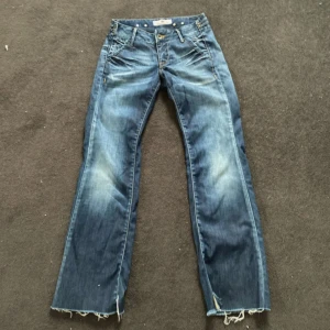 Blå bootcut jeans från Fornarina - Snygga blå jeans från Fornarina med bootcut passform och slitna detaljer vid bensluten. Jeansen har coola kontrastsömmar, flera fickor och klassisk knappgylf. Perfekta för dig som gillar en avslappnad och trendig look. Skulle säga att de både passar S och M 