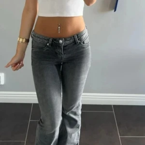 Gråa bootcut jeans med låg midja - Säljer ett par gråa jeans med bootcut-modell och låg midja. Jeansen har klassisk femficksdesign, bälteshällor och dragkedjegylf. Snygg tvätt och passar perfekt till en trendig streetstyle-look.
