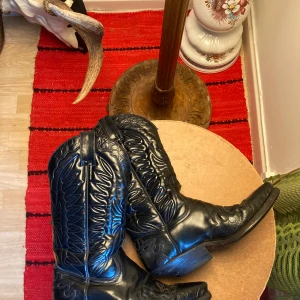 Svarta cowboy boots i skinn - Snygga svarta cowboy boots i äkta skinn med klassiska broderade detaljer och spetsig tå. Inköpta på vinted men är för små. As balla! 