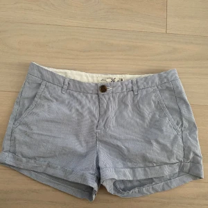 Lågmidjade randiga blå shorts från H&M L.O.G.G. - Snygga blå och vita randiga shorts från H&M L.O.G.G. i klassisk modell med fickor fram och bak, knäppning med knapp och dragkedja samt hällor för bälte. Perfekta för varma dagar och har en avslappnad men stilren look. Skriv vid frågor!!💗 pris kan diskuteras🫶