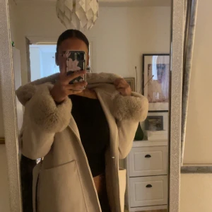 Helt ny beige orcelly kappa  - Säljer en beige pälsjacka från Orcelly i storlek S/M. Jackan har fluffiga pälsdetaljer vid krage och ärmslut, samt ett bälte i midjan för snygg passform. Perfekt för dig som vill ha en varm och trendig look under kyliga dagar. Den är använd bara 1 gång så det är helt ny och inga märken eller skrynklor. 