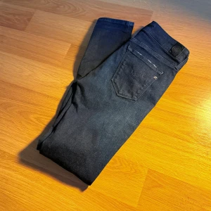 Replay mörkblå jeans - Snygga mörkblå jeans från Replay med klassisk femficksdesign. Jeansen har en diskret tvättad look, silverfärgade nitar och logotypdetalj vid fickan. Perfekta för dig som gillar stilrena och tajta jeans.