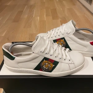 Gucci Ace Tiger  - Snygga skor från Gucci. (ÄKTA) De är i nyskick, och har inga defekter. De passar från 42-43.  🚨| Box ingår och separata dustbags till varsin sko ingår. Nypris-5499 kr | Mitt pris - 2999 kr. . Vill gärna få dessa skor sålda snabbt så pris kan diskuteras vid snabb affär. Hör av er om minsta fundering eller fråga om fler bilder. Tack. 