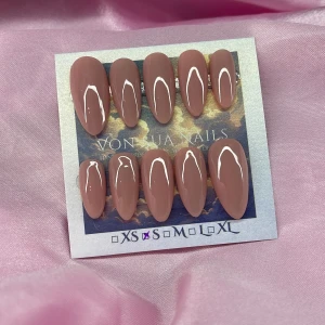 CleanGirl(S); Medium Almond - Snygga mandelformade press-on naglar i en mjuk rosa-brun nyans med glansig finish. Setet innehåller 10 naglar i storlek S: 15 mm, 11,5 mm, 12 mm, 11 mm, 9 mm, perfekta för dig som vill ha en elegant och clean look. Naglarna har en modern, minimalistisk design.
