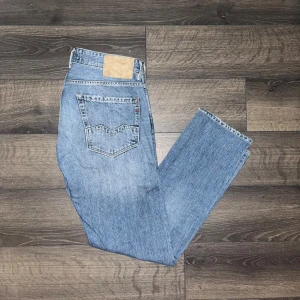 Replay jeans - Snygga Replay Rob jeans i klassisk blå tvätt. Modellen har raka ben, fem fickor och normal passform. Jeansen är tillverkade i slitstarkt bomullsmaterial och har Replay-logga på bakfickan samt läderpatch i midjan. Midja 43cm, längd 100cm. JAG SKICKAR INGA FLER BILDER PÅ NÄR JAG BÄR JEANSEN:) 19