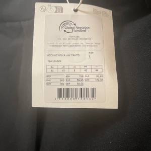 Svarta kostymbyxor från MSCH - Svarta kostymbyxor från MSCH, modell Henrika HW Pants. Byxorna har hög midja, vida ben och är tillverkade av återvunnen polyester. Klassisk look med pressveck och bälteshällor, perfekta för en stilren outfit.