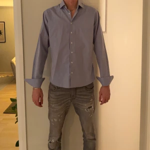 Skjorta - Snygg ljusblå skjorta från iTailor med klassisk krage och vita knappar. Skjortan har lång ärm med manschett och är sydd i ett mjukt bomullstyg. Perfekt för dig som gillar stilrena och enkla plagg med bra passform.